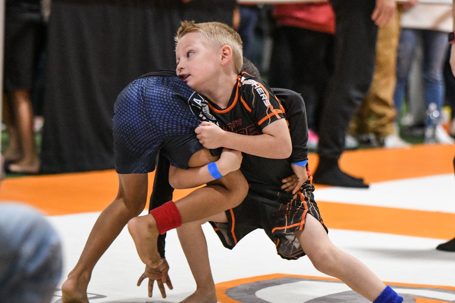 A young 10th Planet student working a body lock at a tournament